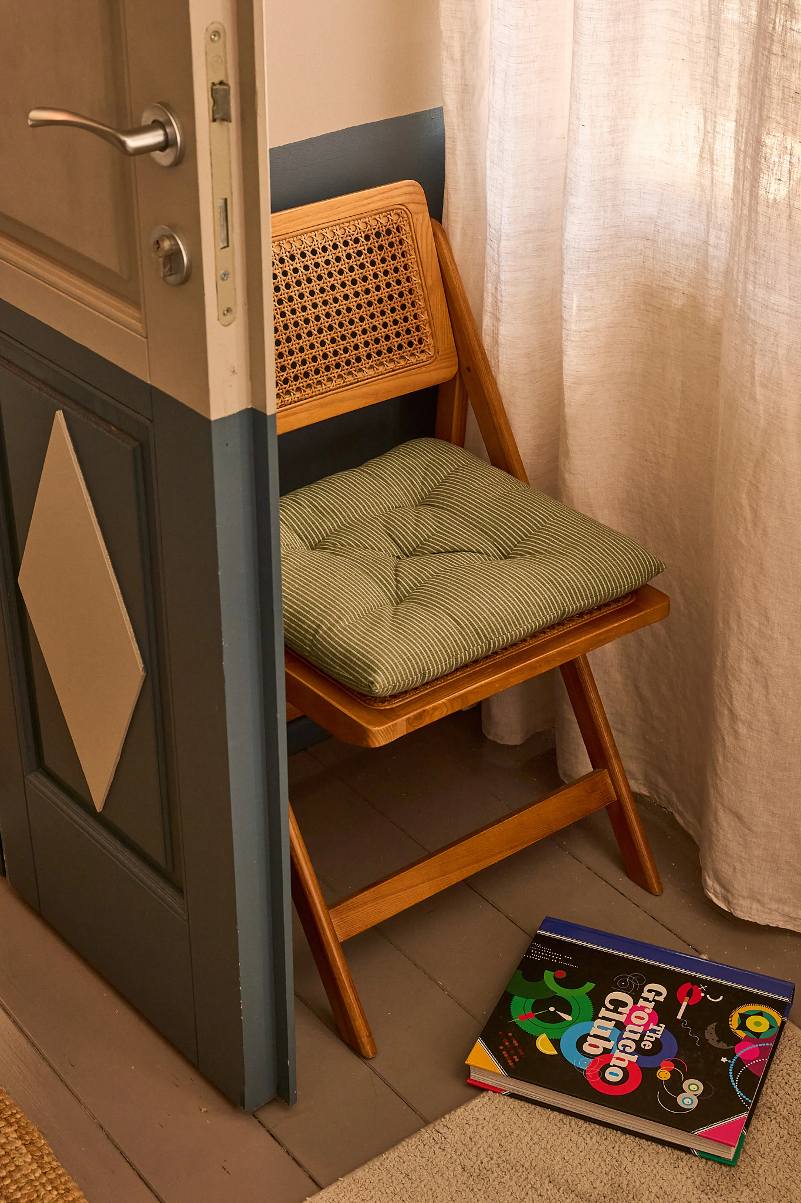 Rattan folding chair with green cushion and books on the floor, Silvija Suite, Hidden House Hvar