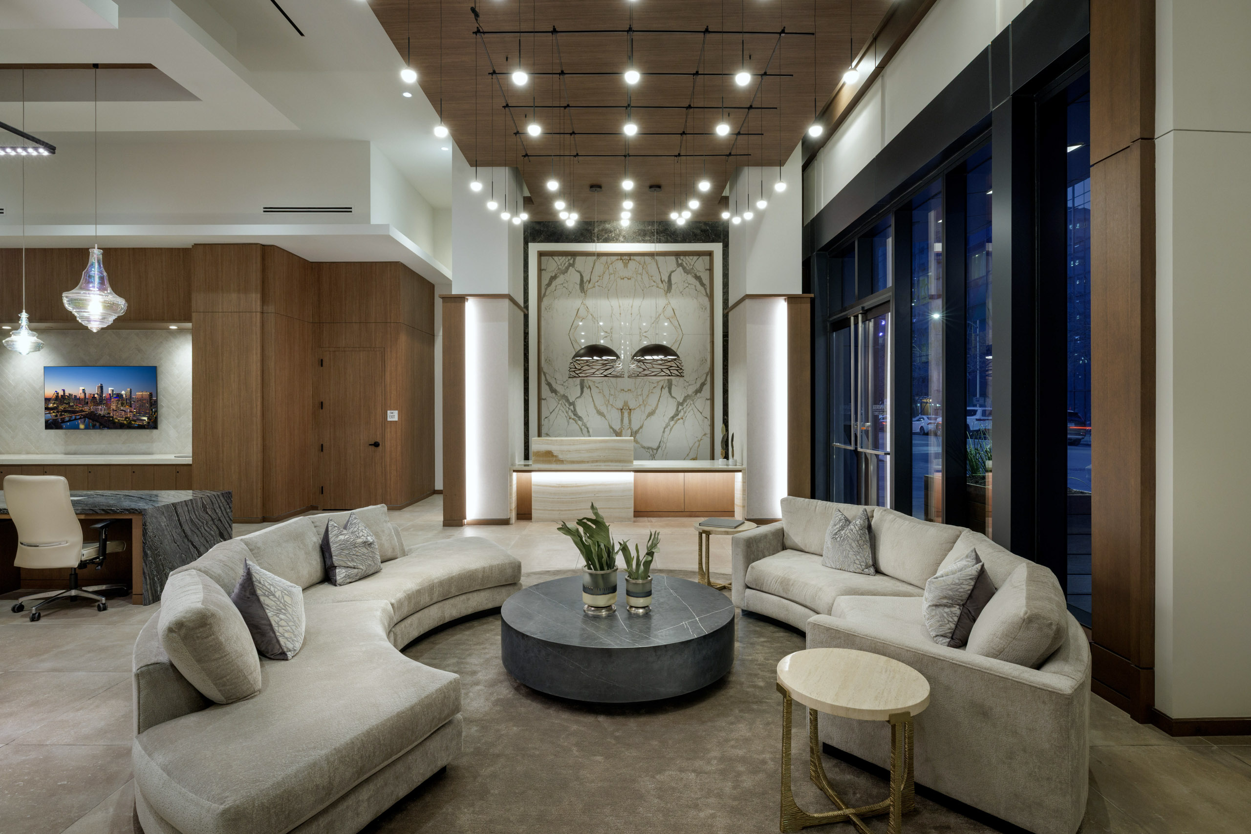 Modern lobby with curved sofas, stone table, and marble reception desk.