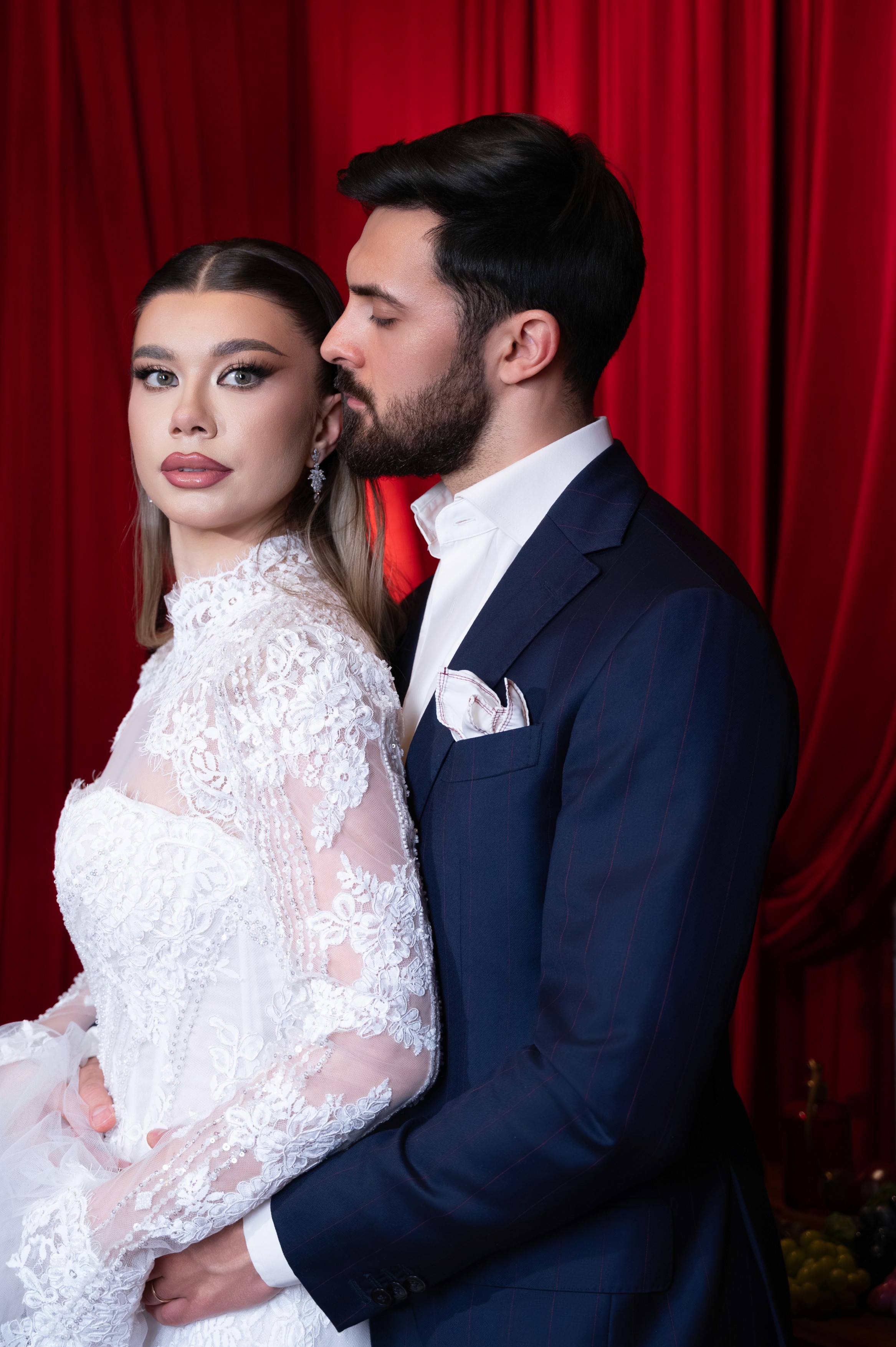 Portret de cuplu cu mireasa și mirele într-un decor dramatic cu draperii roșii, ședință foto de nuntă în București