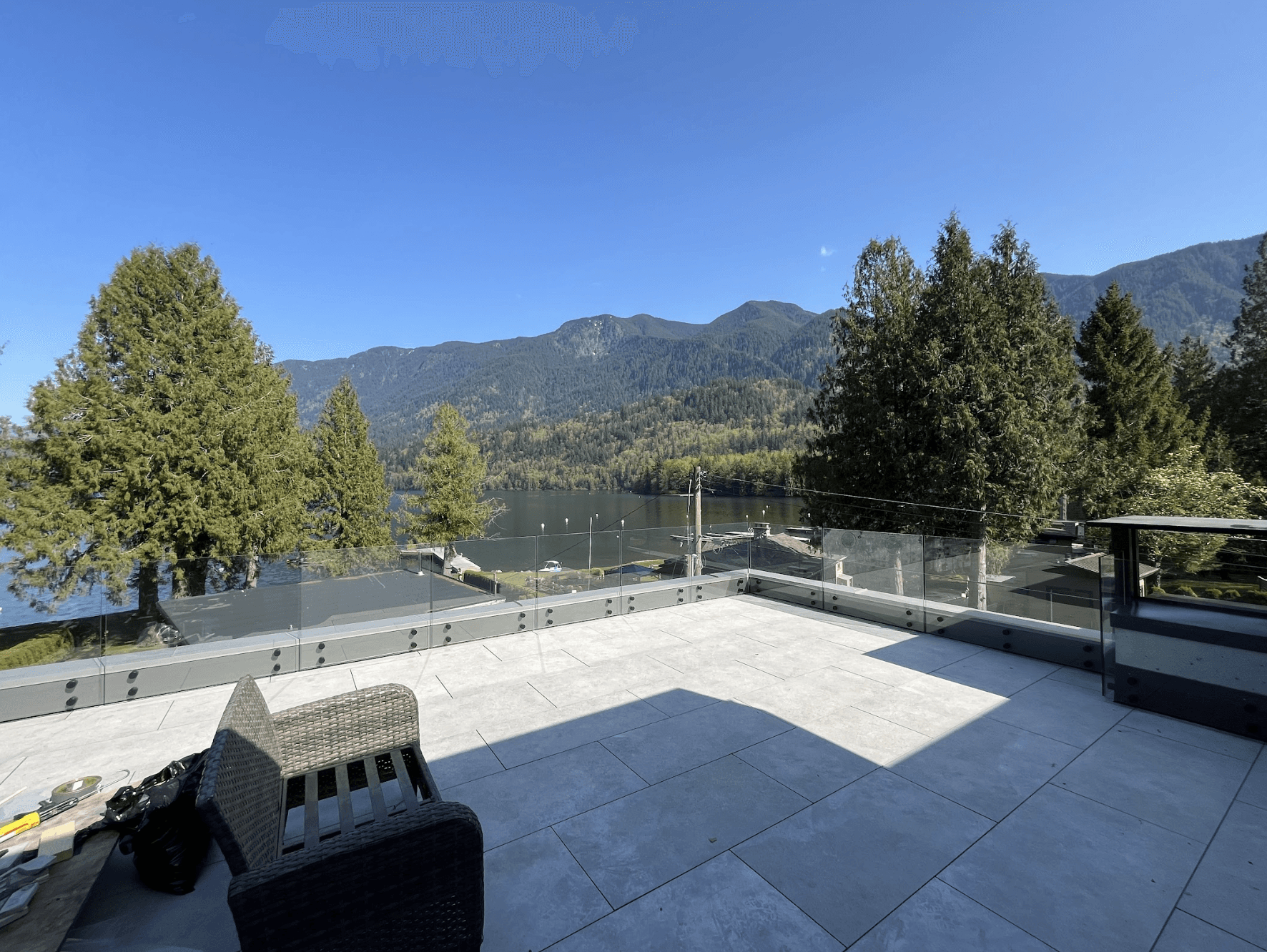 Glass railing on a BC lakeside patio with mountain and forest views