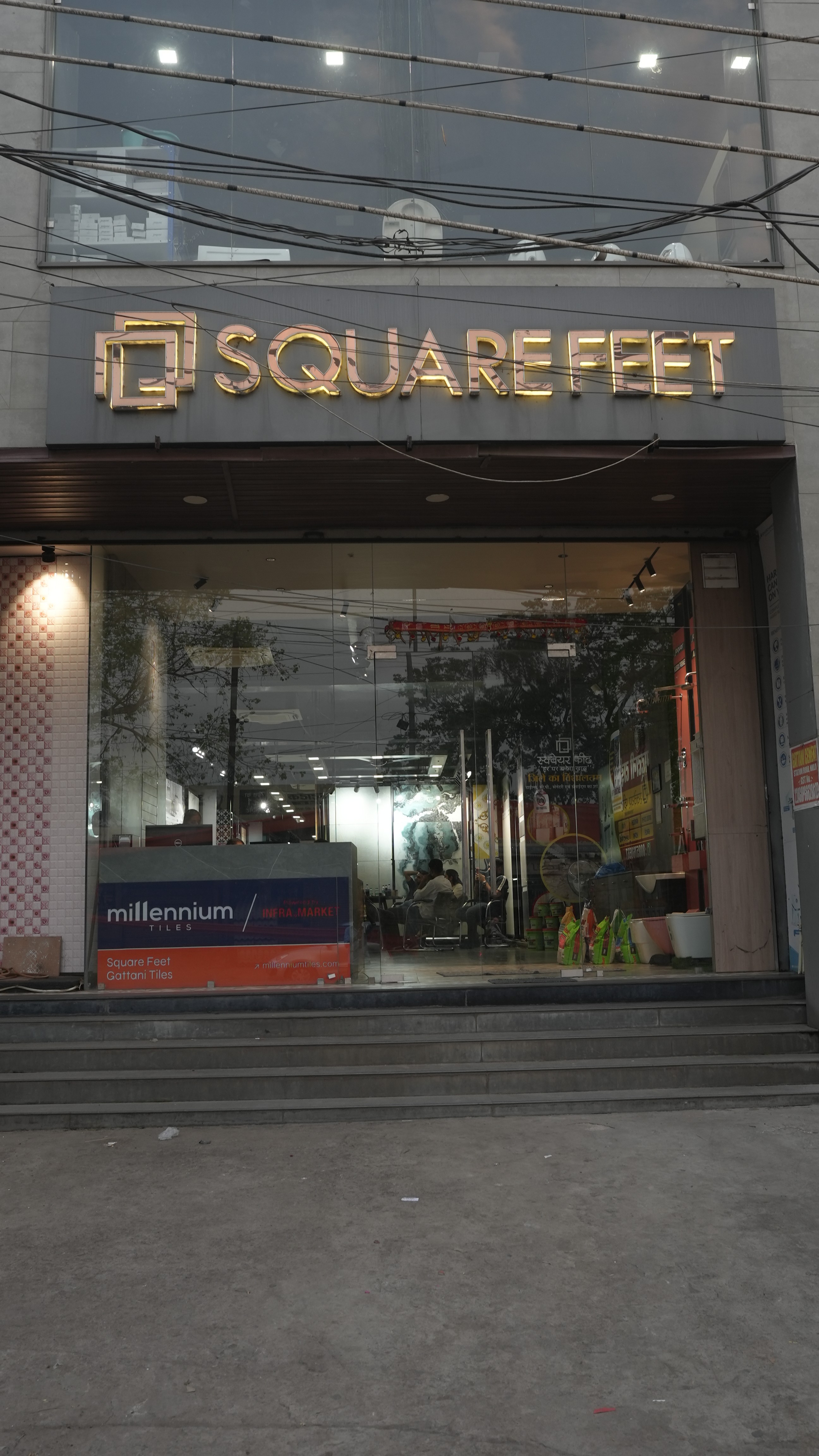 A serene outdoor seating area with two chairs, surrounded by lush greenery and a glassed-in structure.