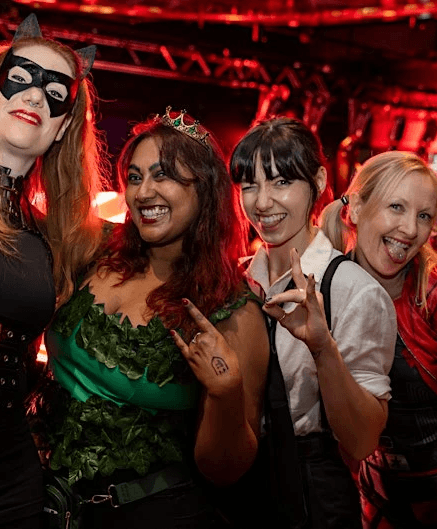 four friends pose in halloween costumes in the arena