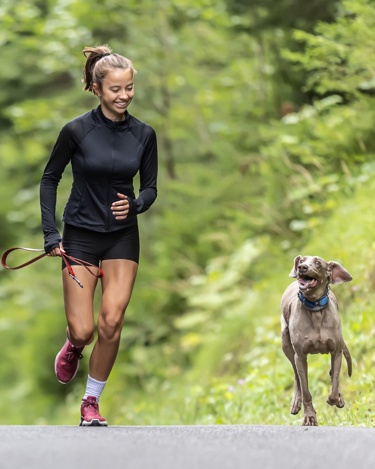 Sporty girl running with her dog, both wearing PetLink GPS trackers