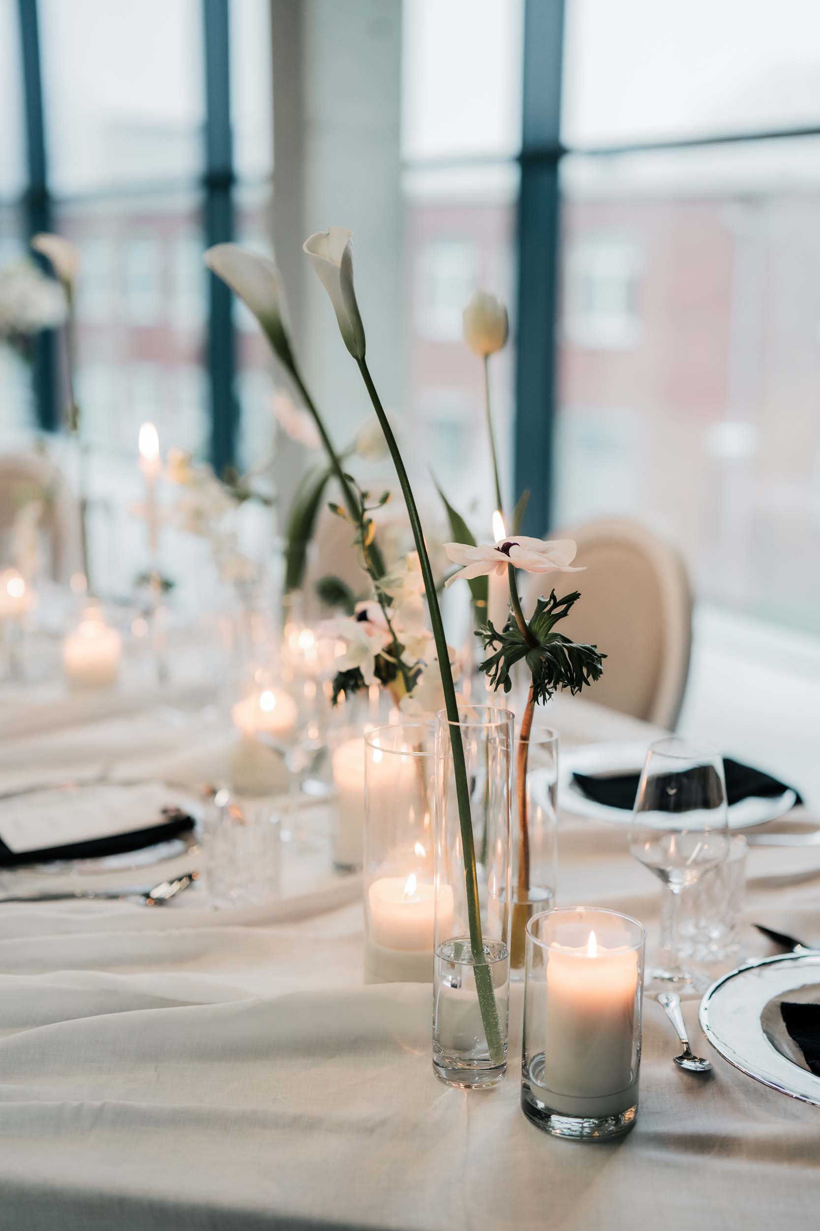 Nahaufnahme von Kerzenschein und weißer Floristik und Tischdekoration.