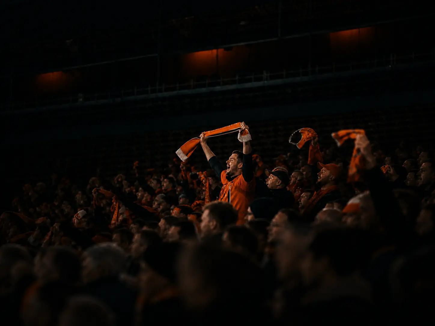 Passionate football fan holding a scarf above the crowd in a packed stadium
