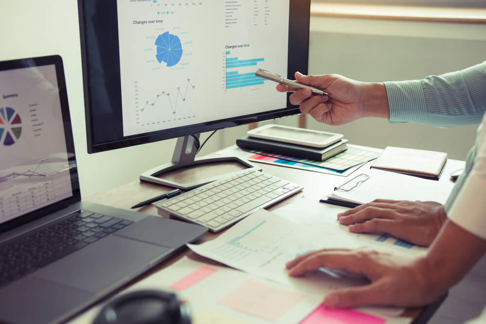Business professionals analyzing financial charts and graphs on computer screens and documents