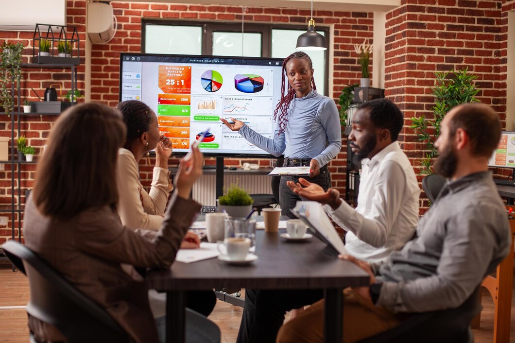 Black woman points to screen at meeting
