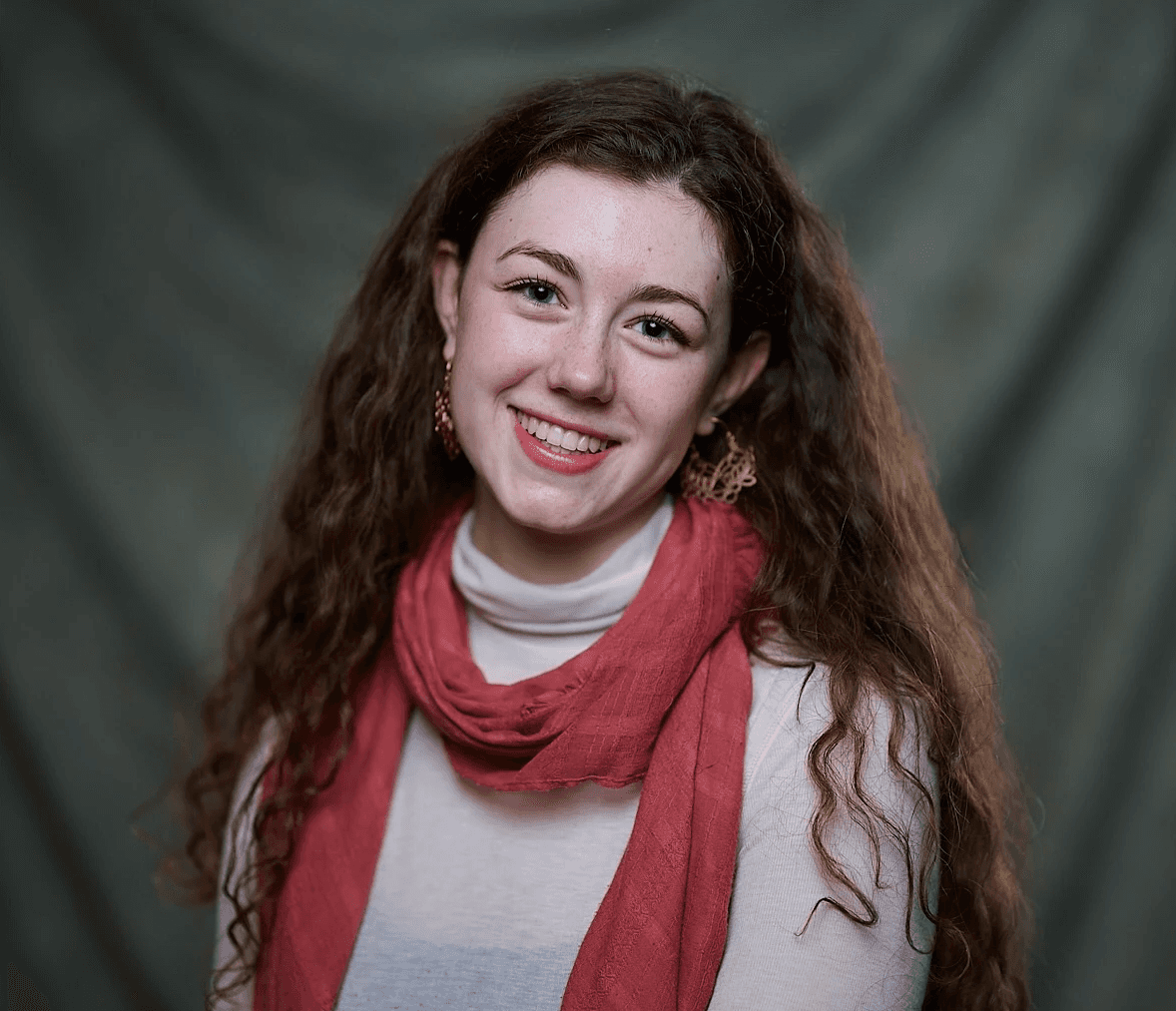 A thoughtful young person with dark hair gazes to the side, captured in soft black and white lighting.