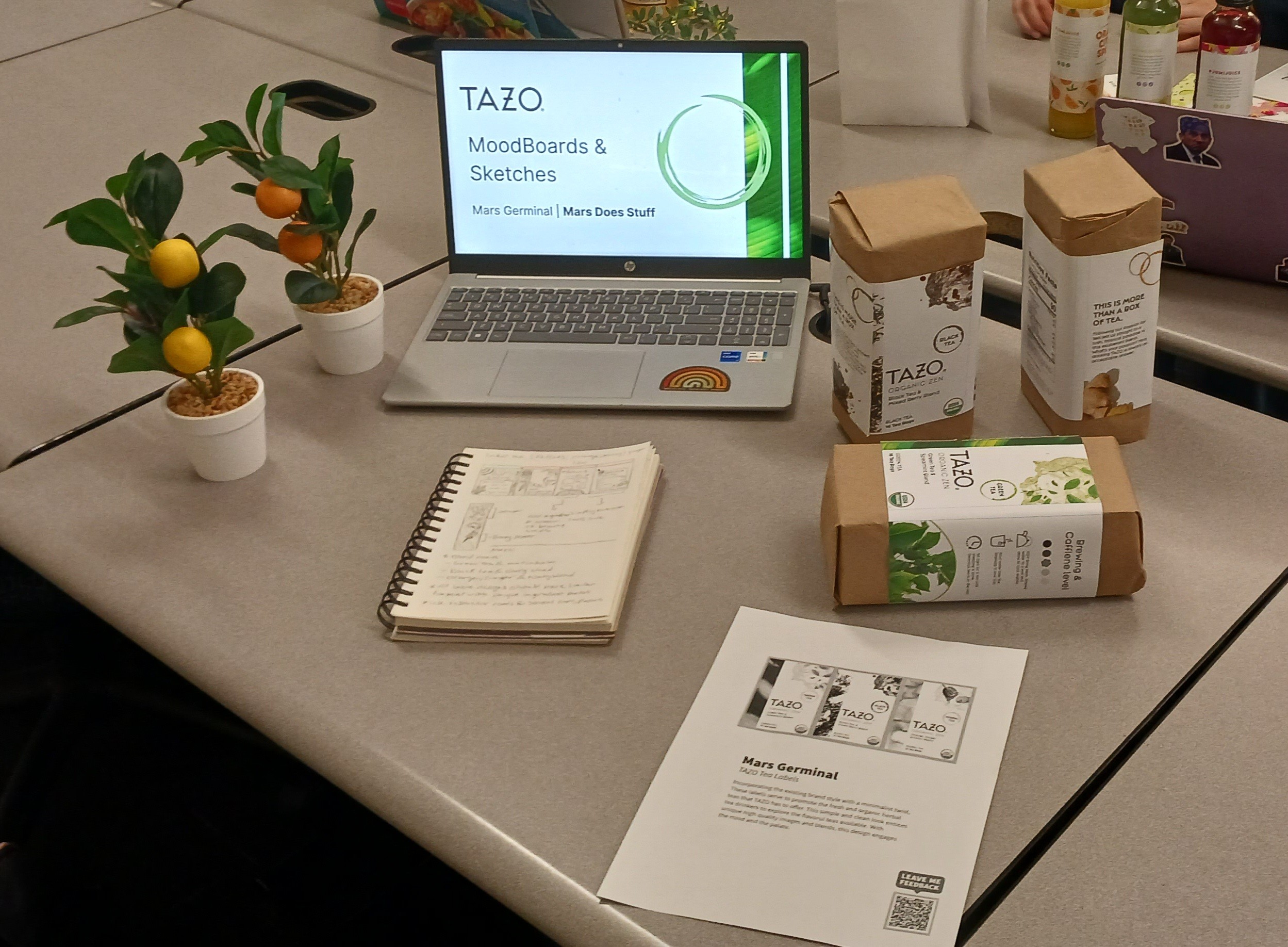 a showcase of thos labels on boxes laid down on a table with plants and a computer