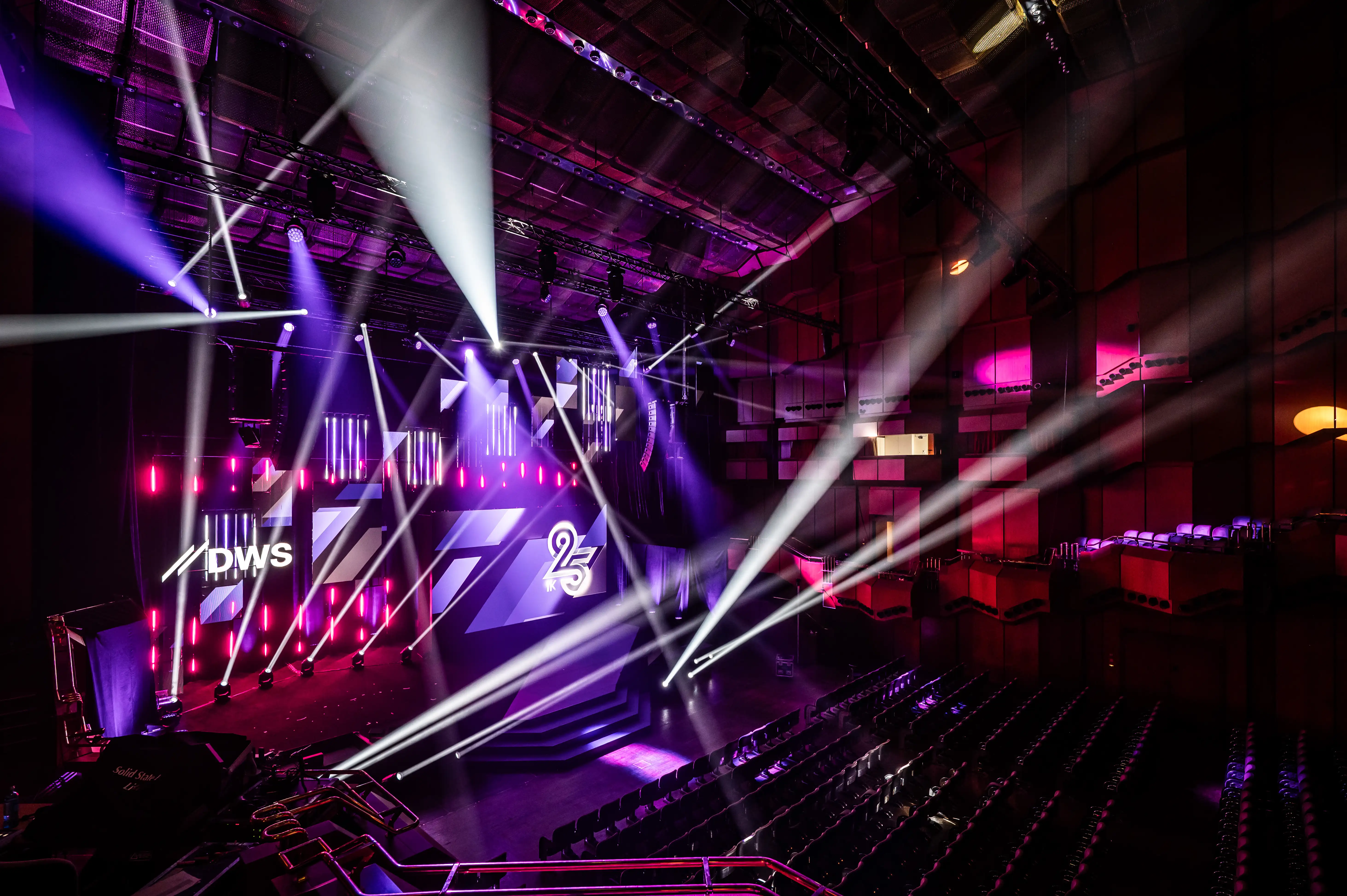 DWS show stage with 25 logo, LED walls and white light beams in the pink-lit hall.