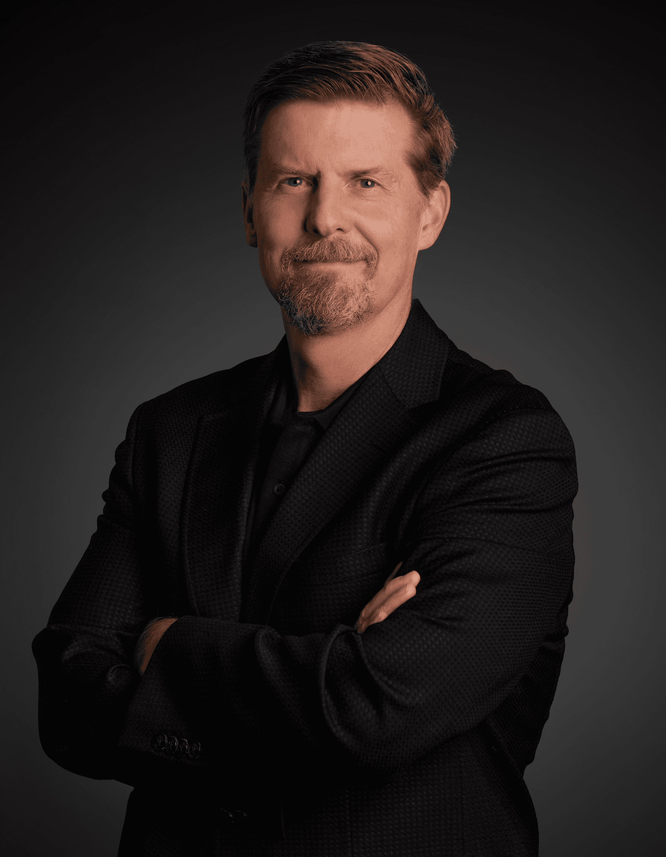 A young person with long, wavy hair sits in front of a plain background, looking directly at the camera.