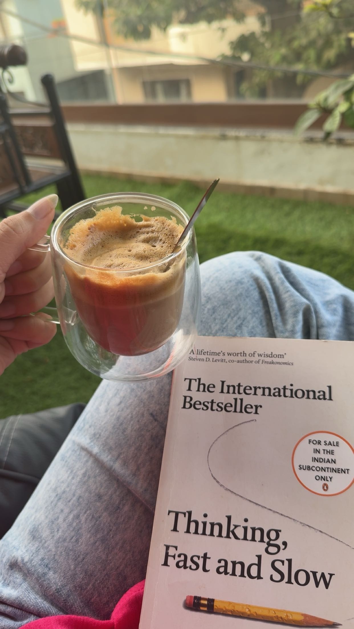 A view from an airplane window shows the aircraft's wing with a golden hue reflecting the setting sun, against a serene backdrop of fluffy clouds and a clear sky.