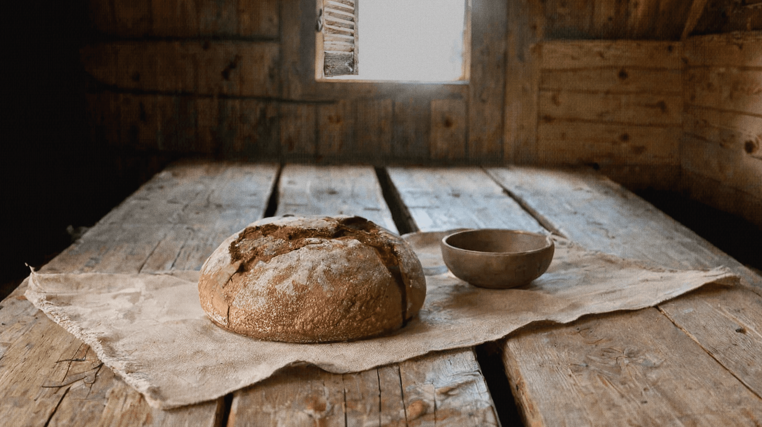 Sacred artwork by Faith and Verse. © Faith and Verse, 2026. All rights reserved. Traditional Pan Ner rye bread on wooden table, 6th-century Alpine peasant interior.
