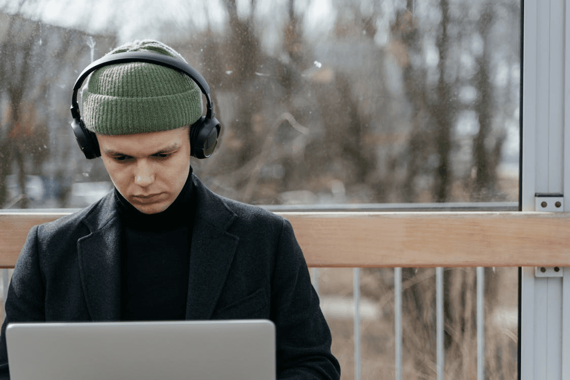 A Man in Green Beanie and Black Headphones