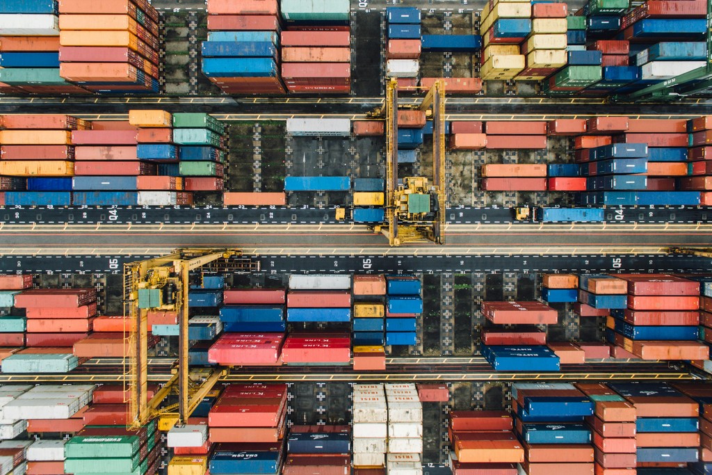 Aerial view of a busy shipping yard filled with colorful stacked containers and cranes, showcasing global logistics and transportation infrastructure.