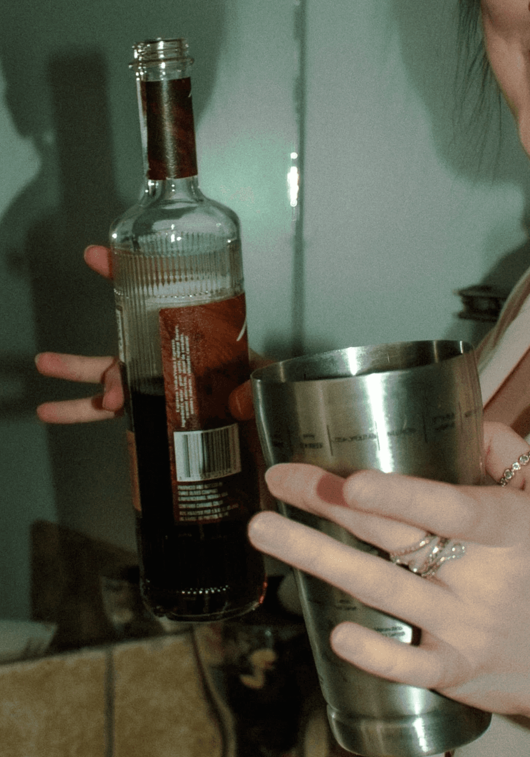 A person in a sparkly green dress lounges with one leg raised, holding a drink, against a festive background.