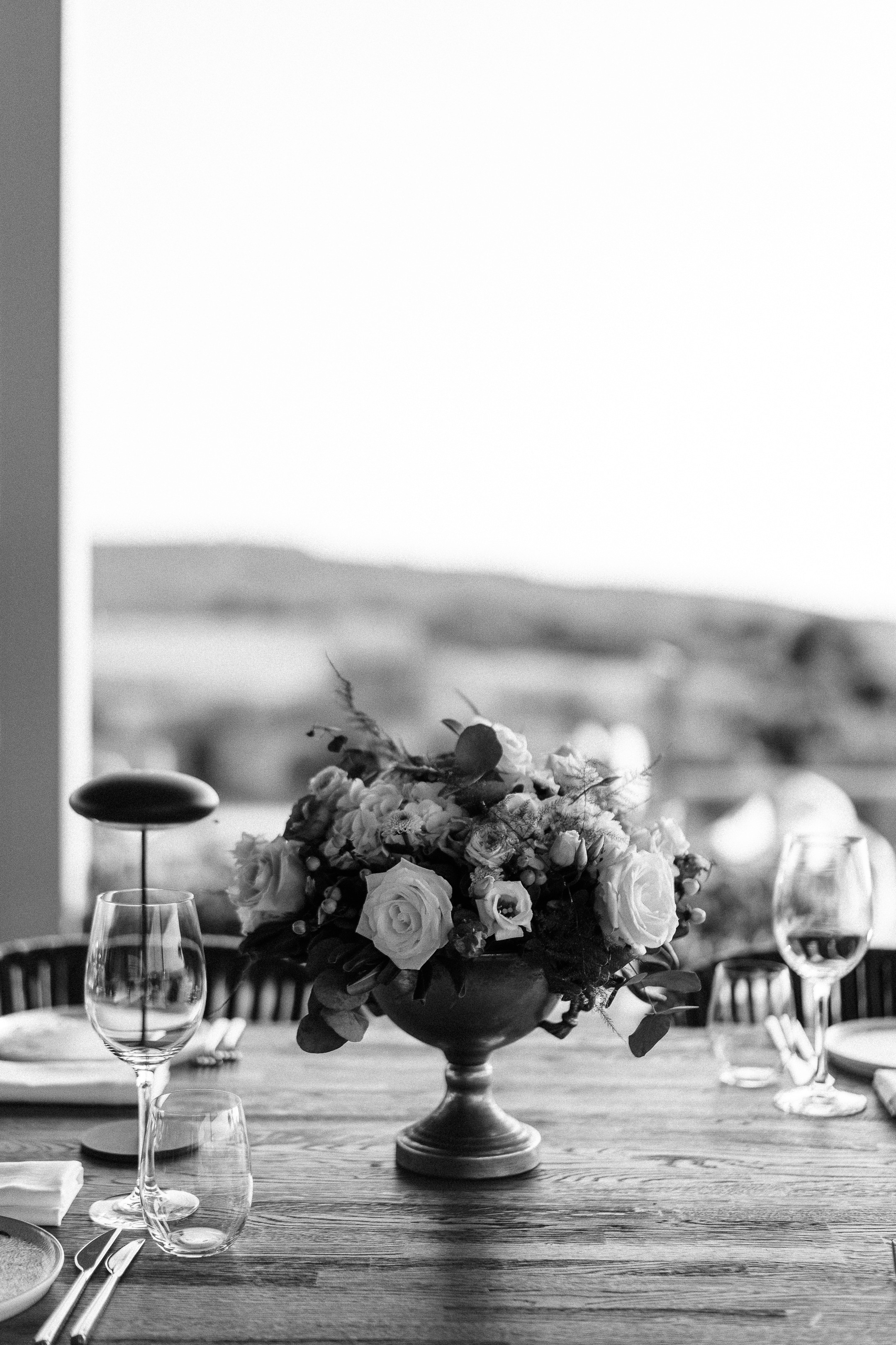 Elegant black and white outdoor wedding reception table setting with a bespoke floral centerpiece in Greece