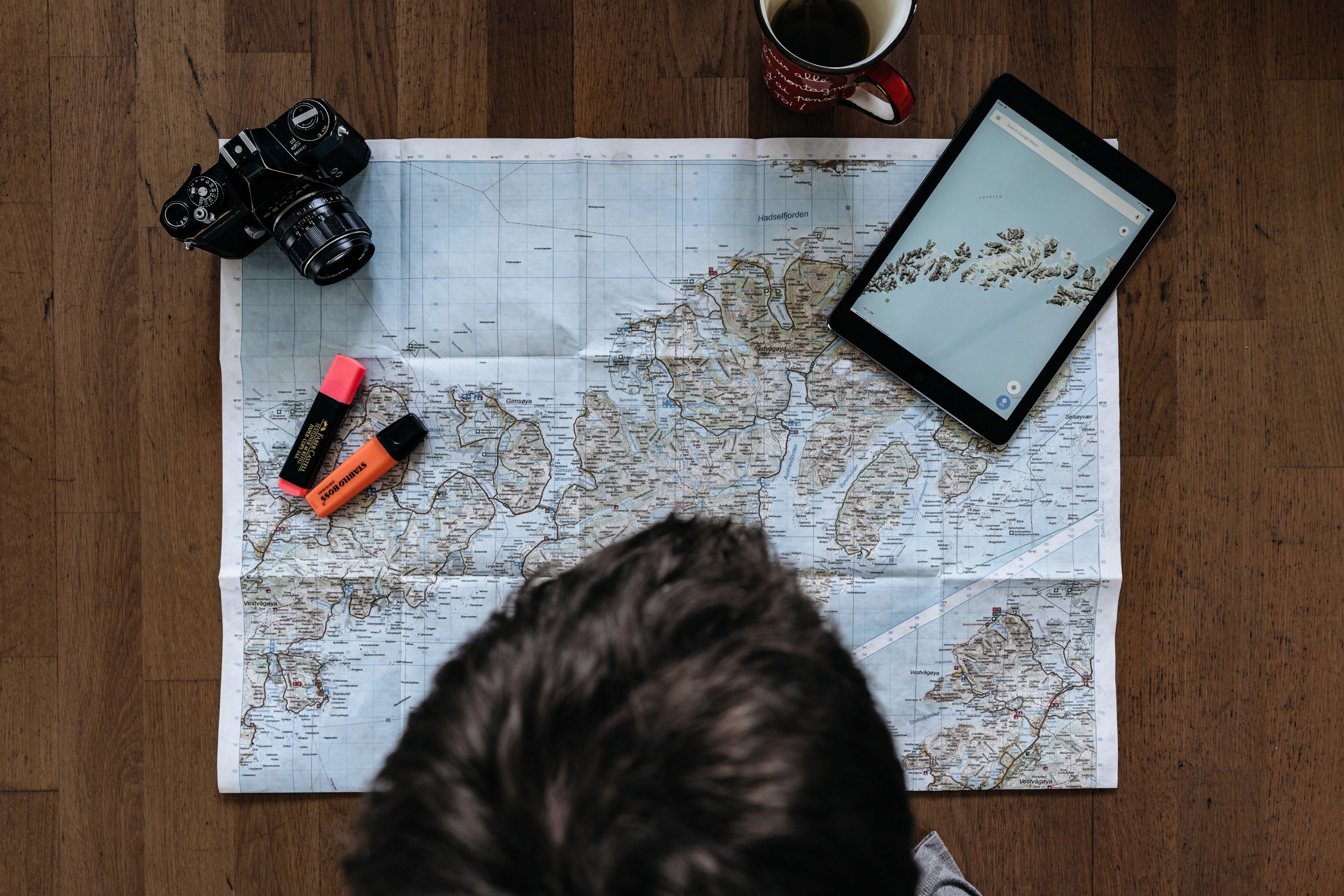 Person looking at map on a table, with camera and tablet