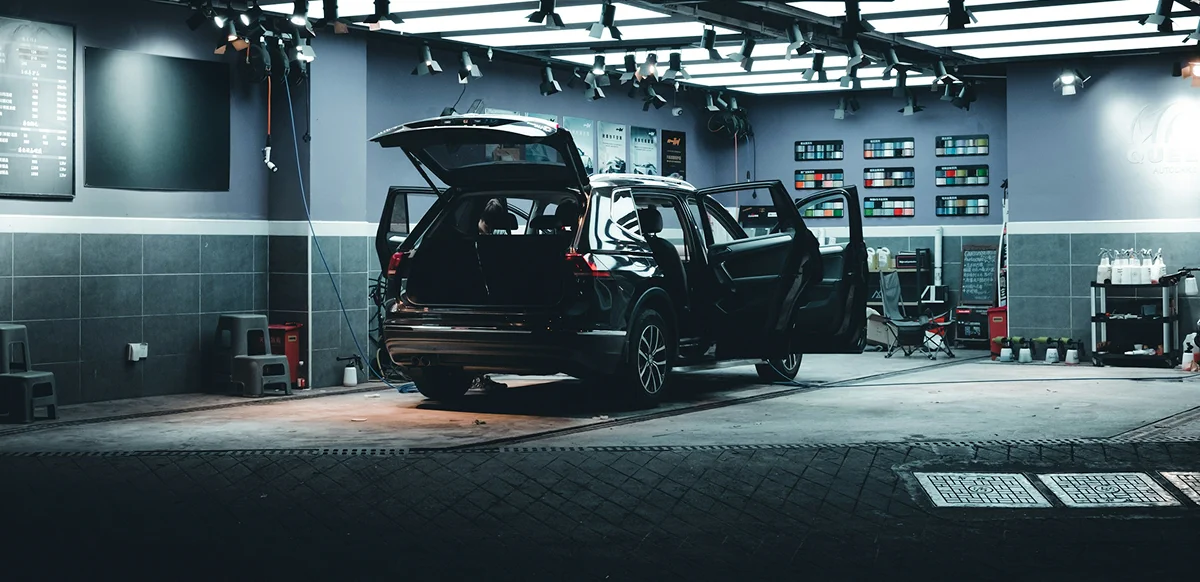 Black SUV prepared for detailing with doors and liftgate open inside a modern auto care garage