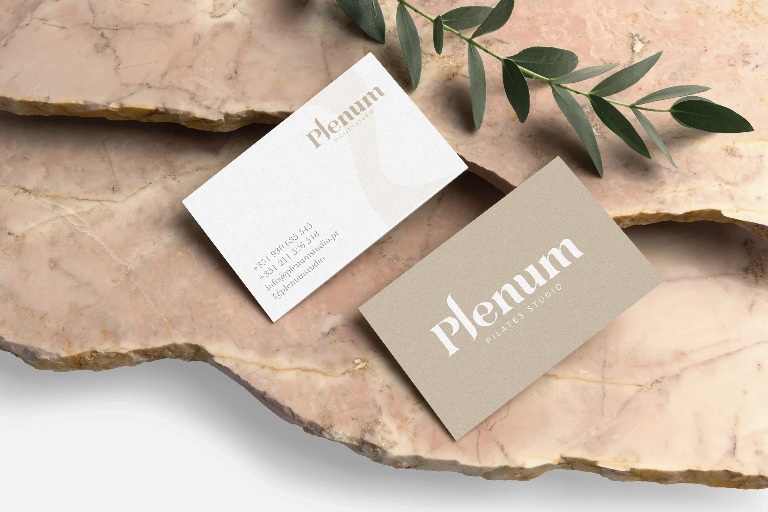 Business card design for Plenum Pilates Studio showcasing elegant typography and minimalist wellness branding on a natural stone background.