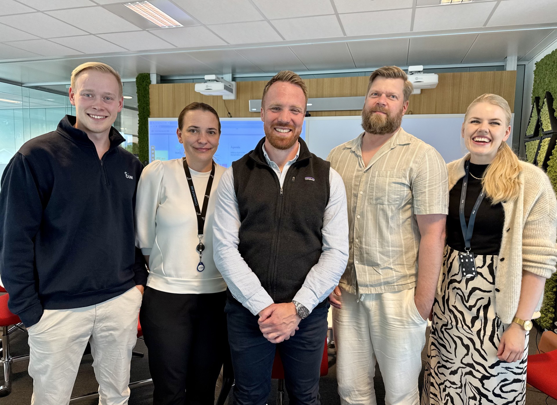 A person wearing a virtual reality headset stands in front of multiple screens, engaged in a digital experience.