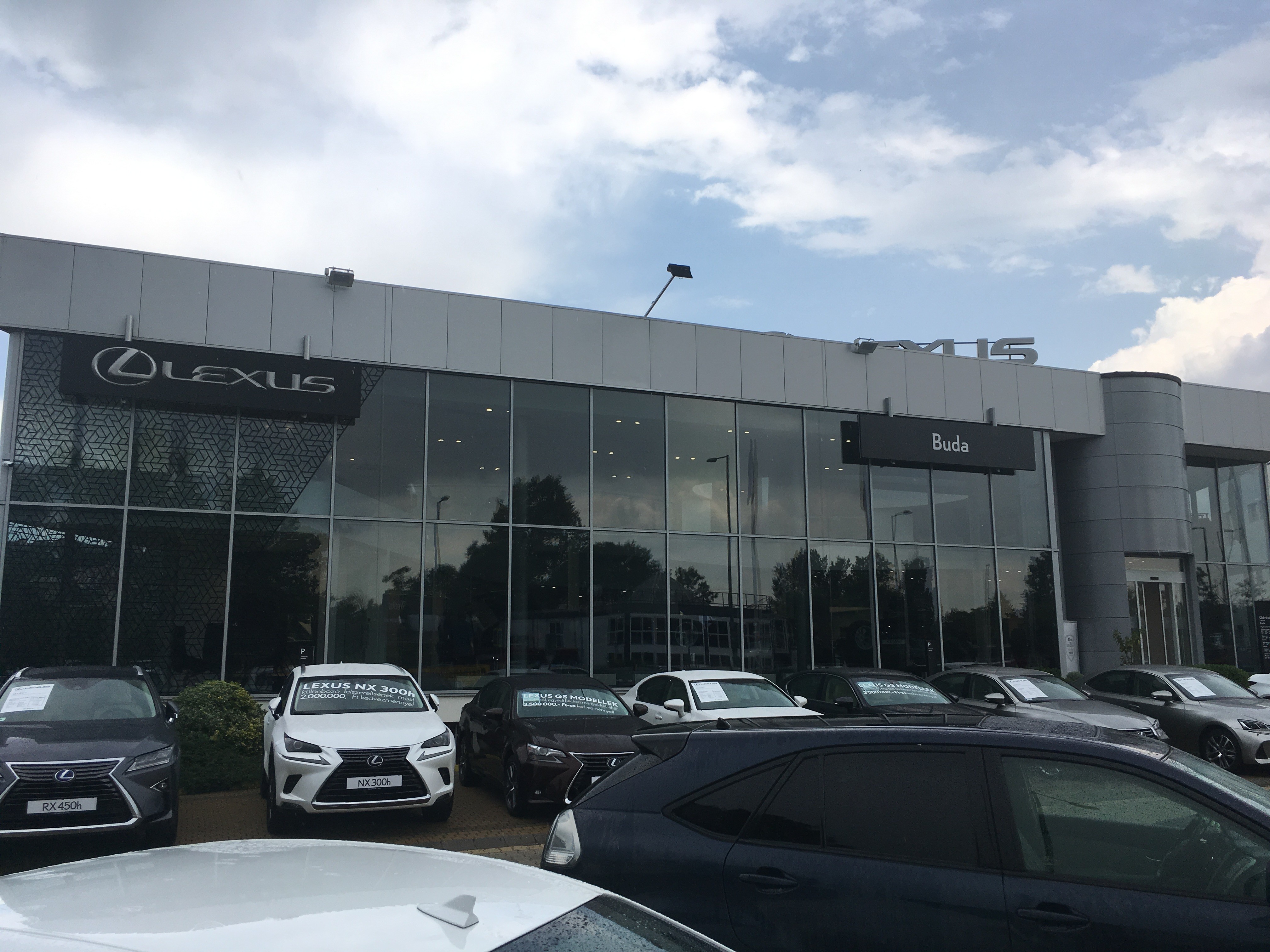 A Lexus Buda autószalon hatalmas üveghomlokzata kívülről fotózva, prémium tükröződő belső hővédő ablakfóliával ellátva. A Nortek által kivitelezett épületfólia elegáns megjelenést ad, miközben drasztikusan csökkenti a bemutatóterem nyári felmelegedését.