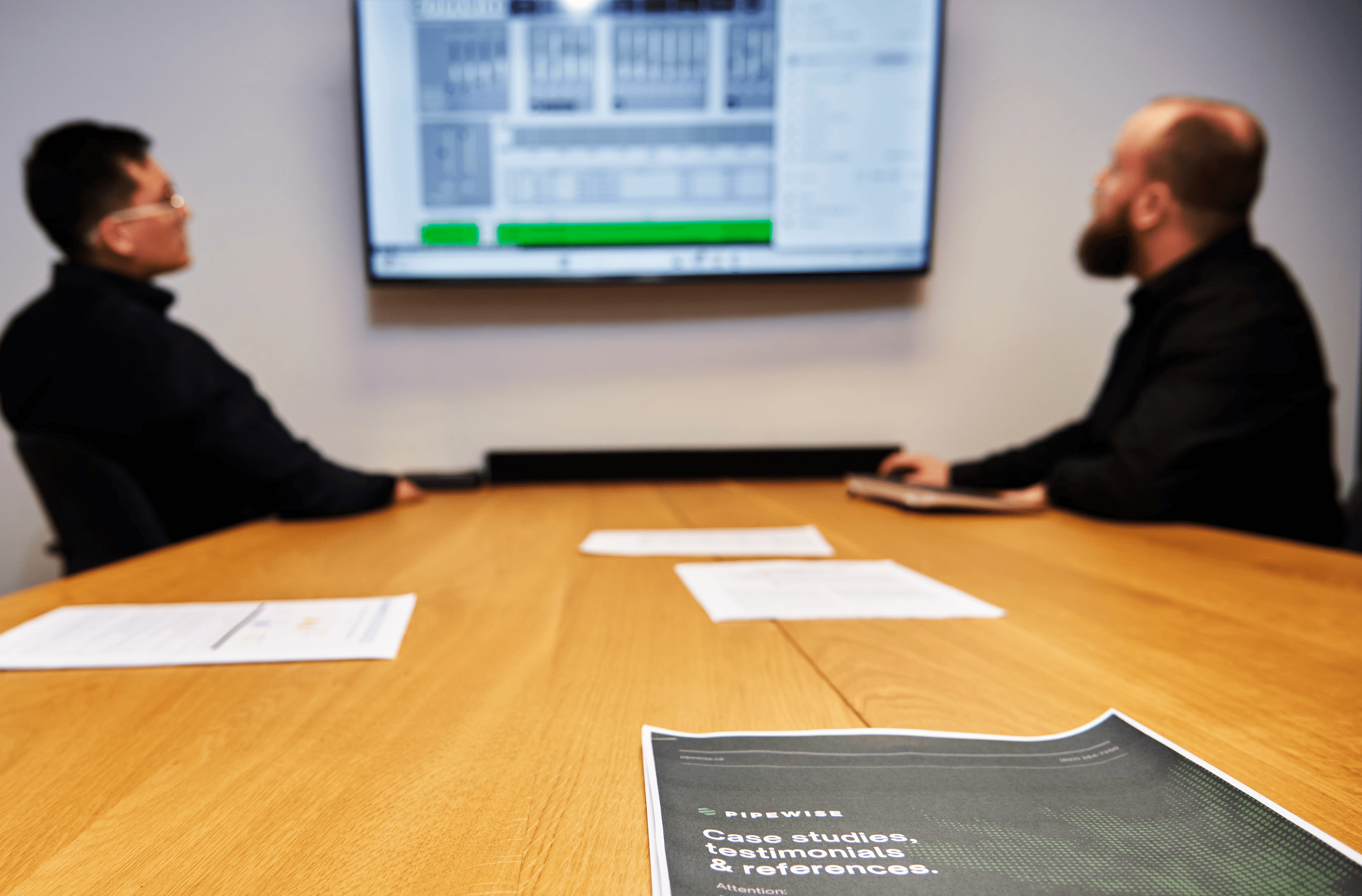 Four diverse professionals collaboratively working on a laptop, with one person pointing at the screen while others observe.