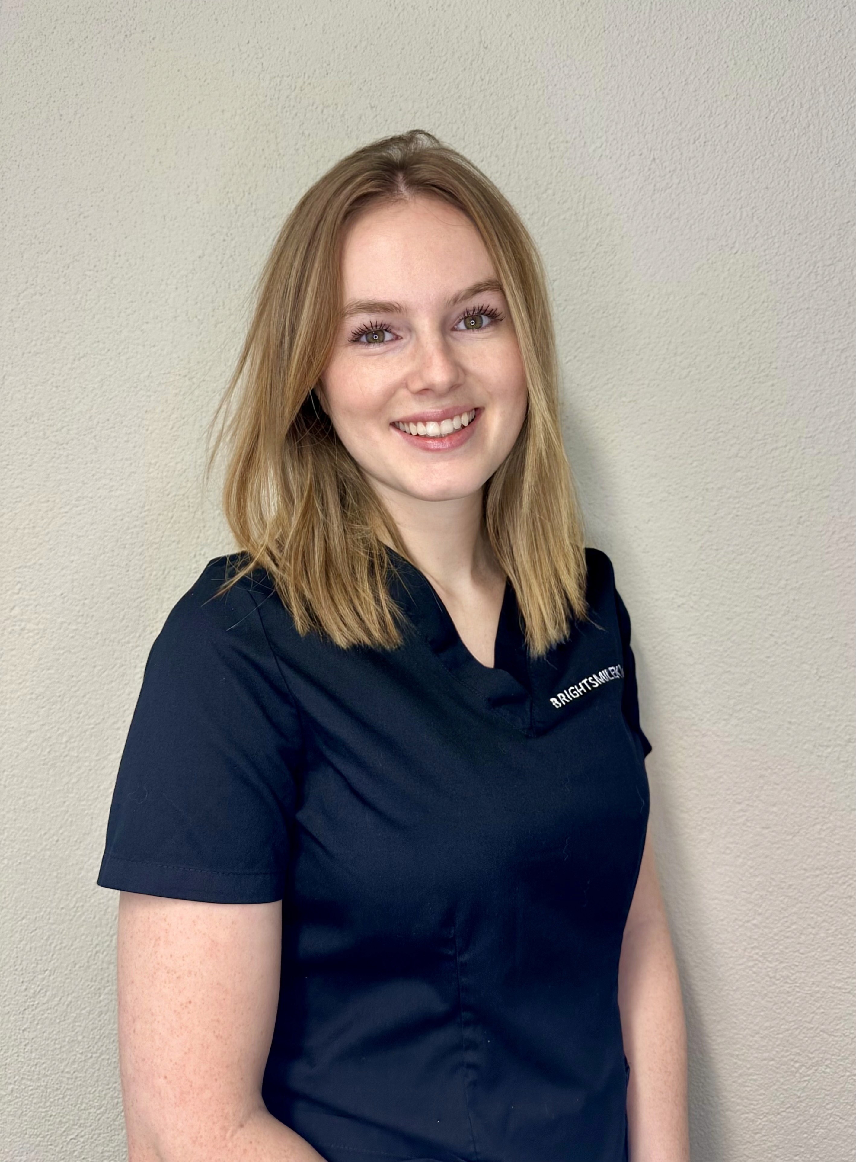 Dentalassistentin Diana Reichmuth im Portrait mit kurzem blonden Haar und breitem Lächeln. 