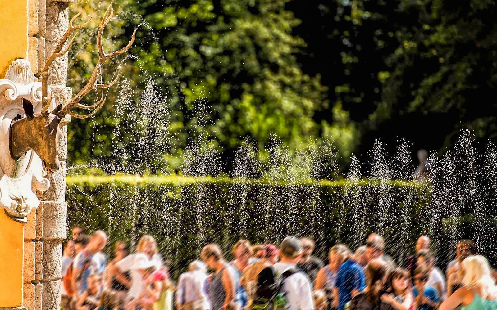 Visitors enjoying water trick fountains at Hellbrunn Palace, Salzburg.