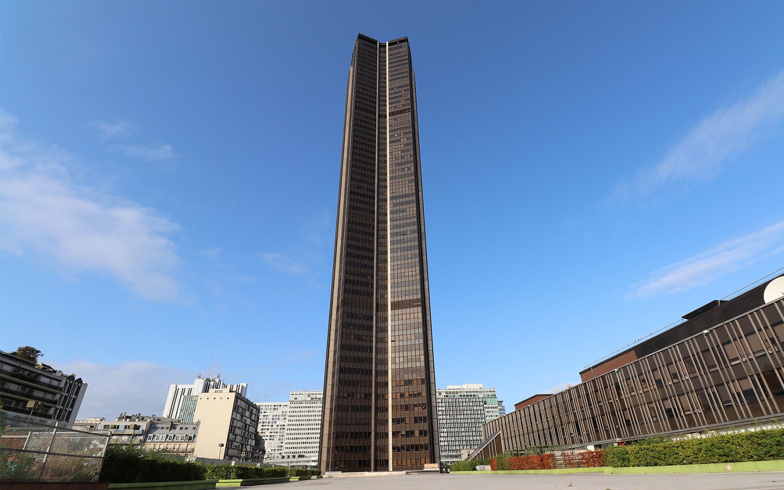 Montparnasse Tower in Paris under a clear blue sky.