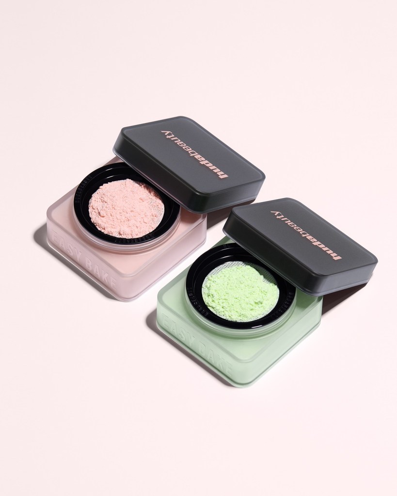 Two containers of powder makeup products, one with pink powder and the other with green powder, both labeled 'EASY BAKE' against a pale pink background.