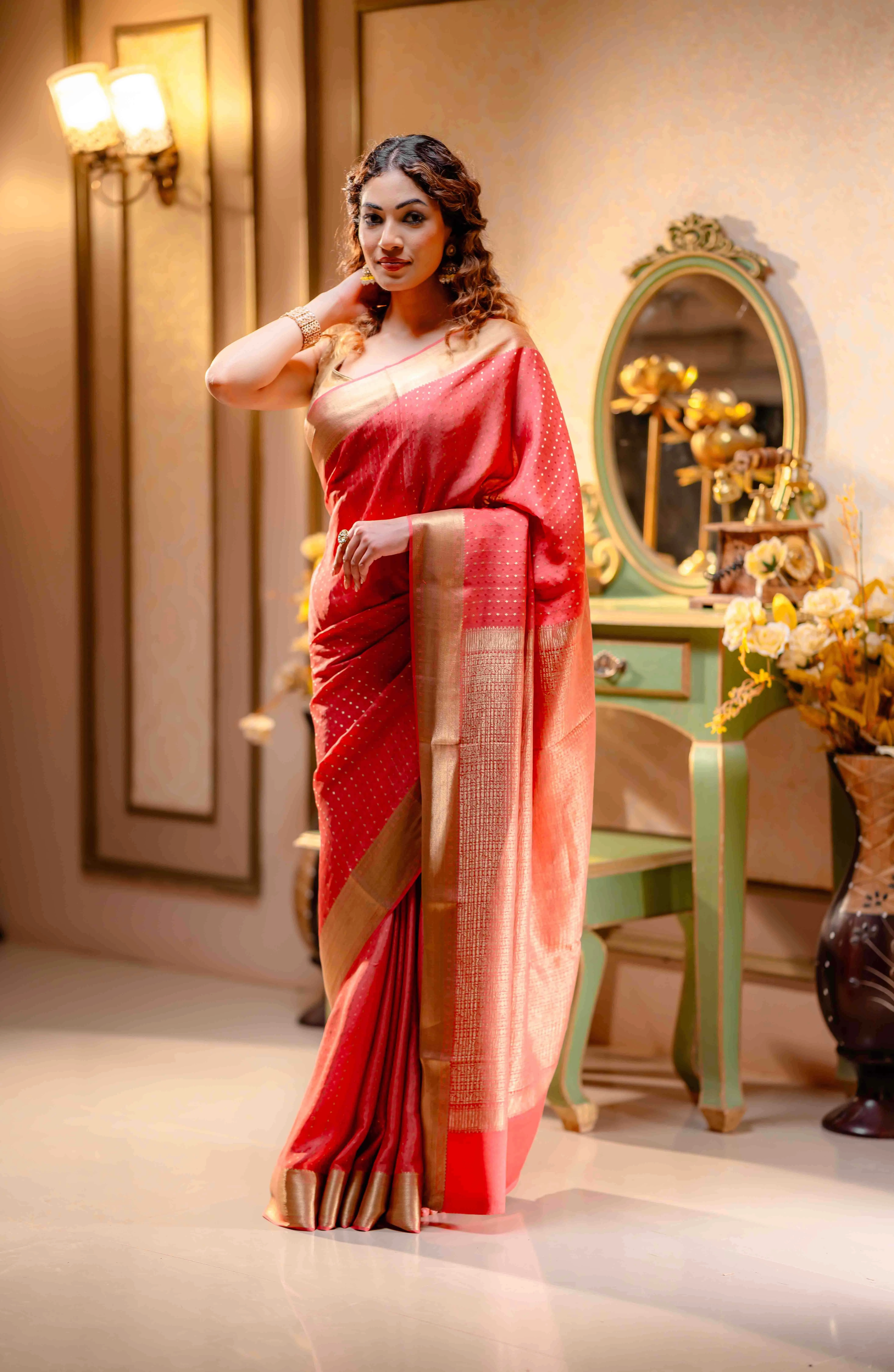 A woman wearing a cream saree paired with a blue blouse from That Saree Shop, standing before a striking blue wall adorned with beige Jaipur prints, creating a perfect blend of traditional elegance and artistic ambiance.