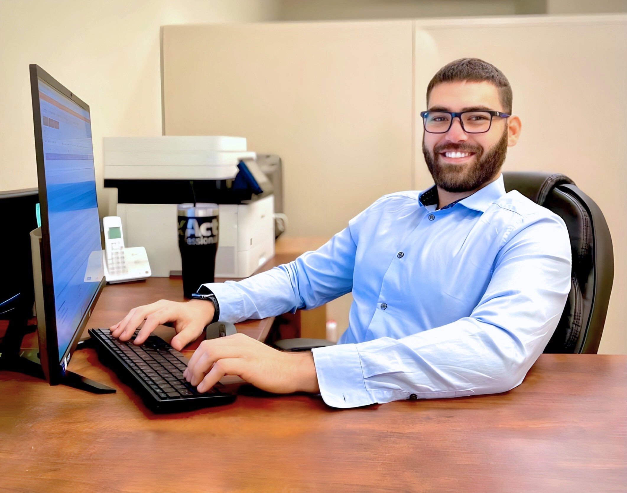 A man in glasses, Joey from Taxes 247, sits at a desk working on his computer.