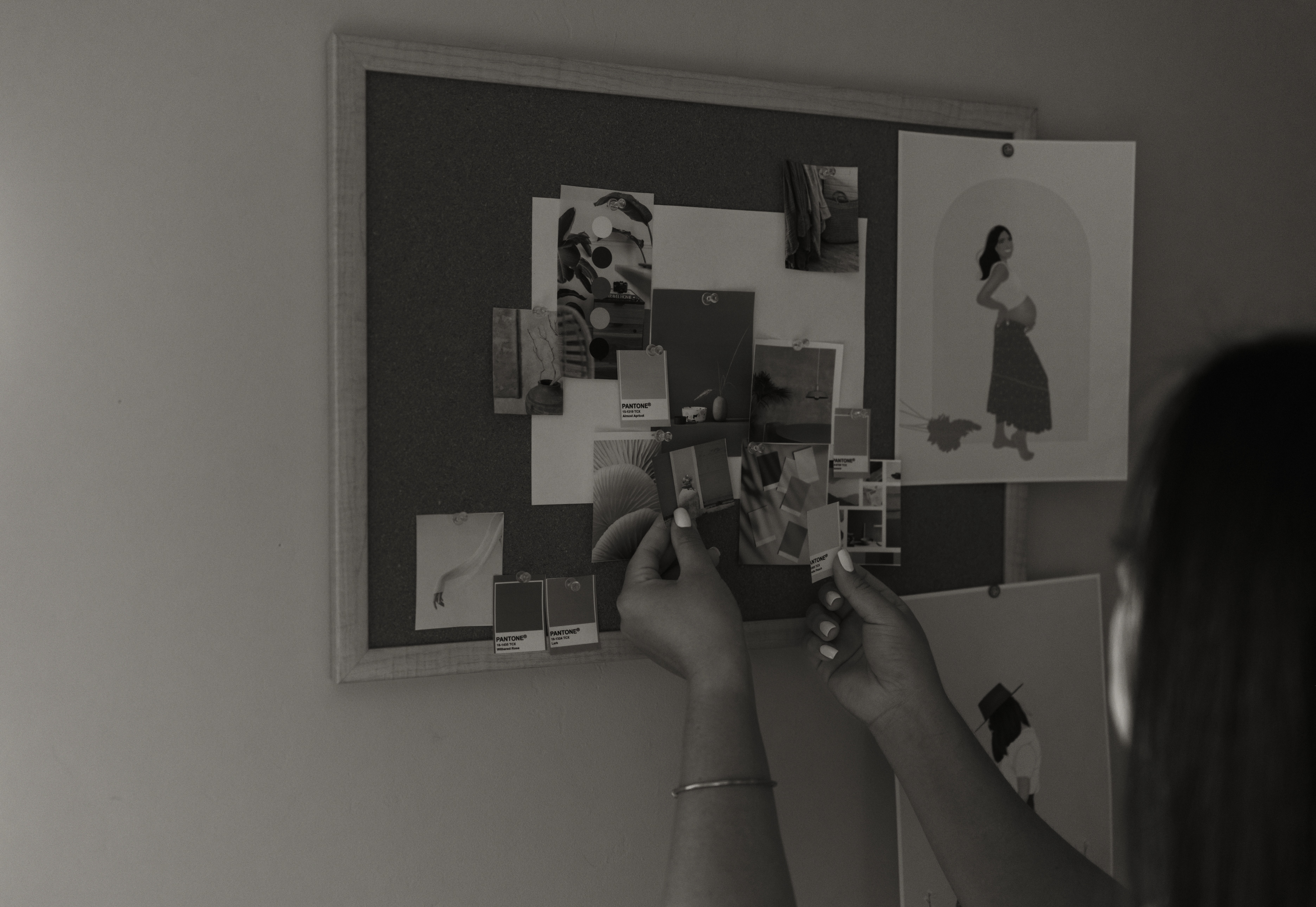 A thoughtful young person with dark hair gazes to the side, captured in soft black and white lighting.
