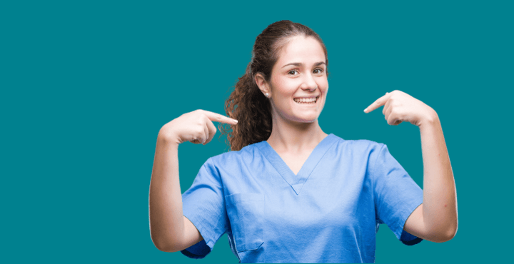Smiling healthcare worker in scrubs pointing at herself on a green background
