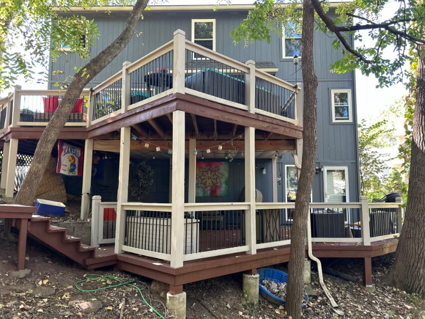 An image of a two story deck with brown flooring and white railing.