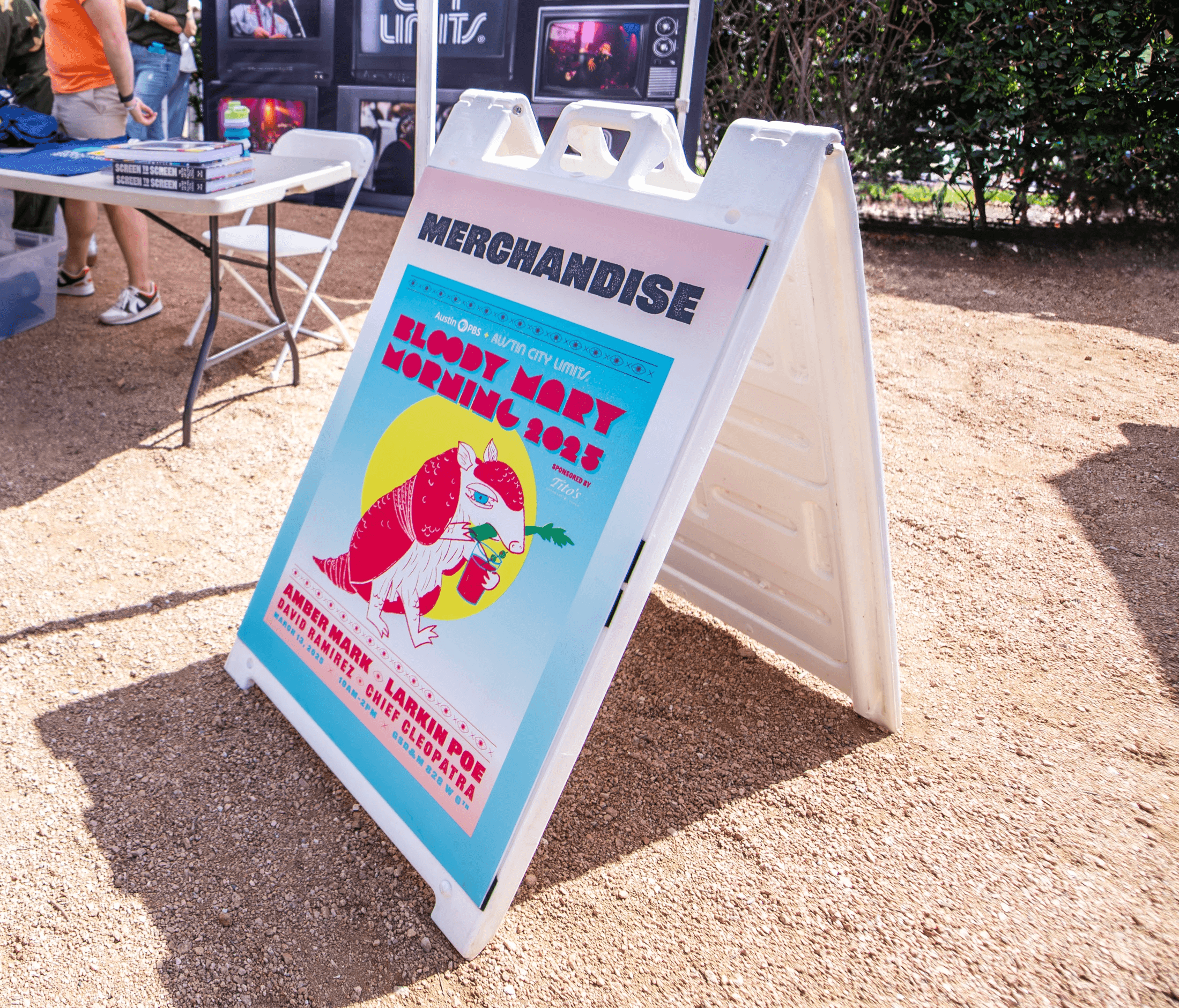 A frame sign reading "Merchandise" with a photo of event poster
