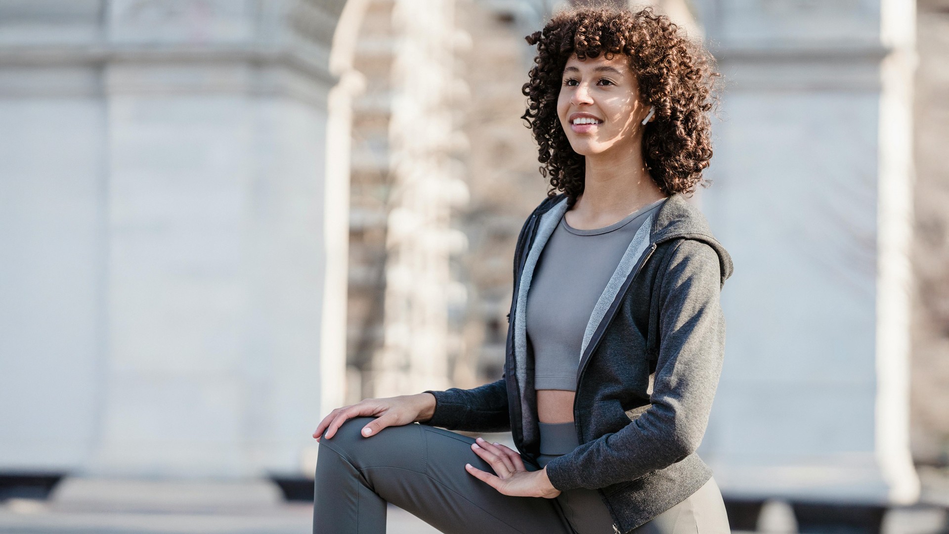 Selbstbewusste sportliche Frau in moderner Trainingskleidung steht im warmen Tageslicht im Freien, mit natürlicher Hautstruktur und ruhigem Gesichtsausdruck, Symbol für Achtsamkeit, Balance und einen bewussten Umgang mit Fasten