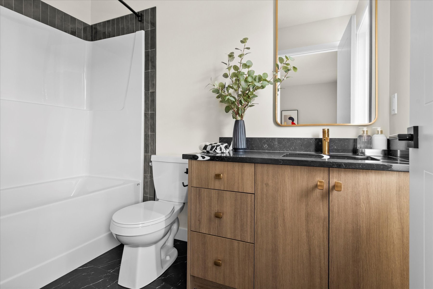 Heartland bathroom finished: wood vanity, black counter, brass fixtures and styled accessories