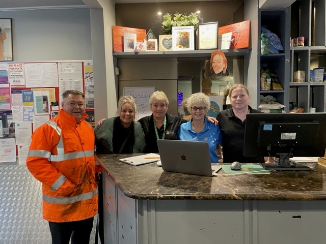 Modern glass building with illuminated facade and trees at sunset