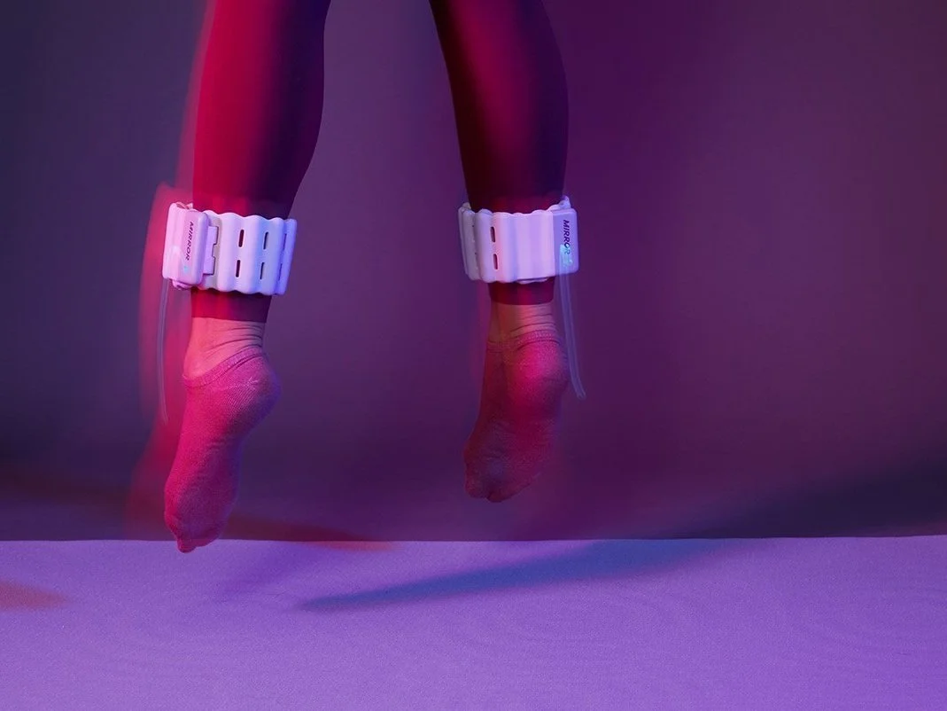 Person jumping while wearing white Lululemon Studio ankle weights in purple lighting