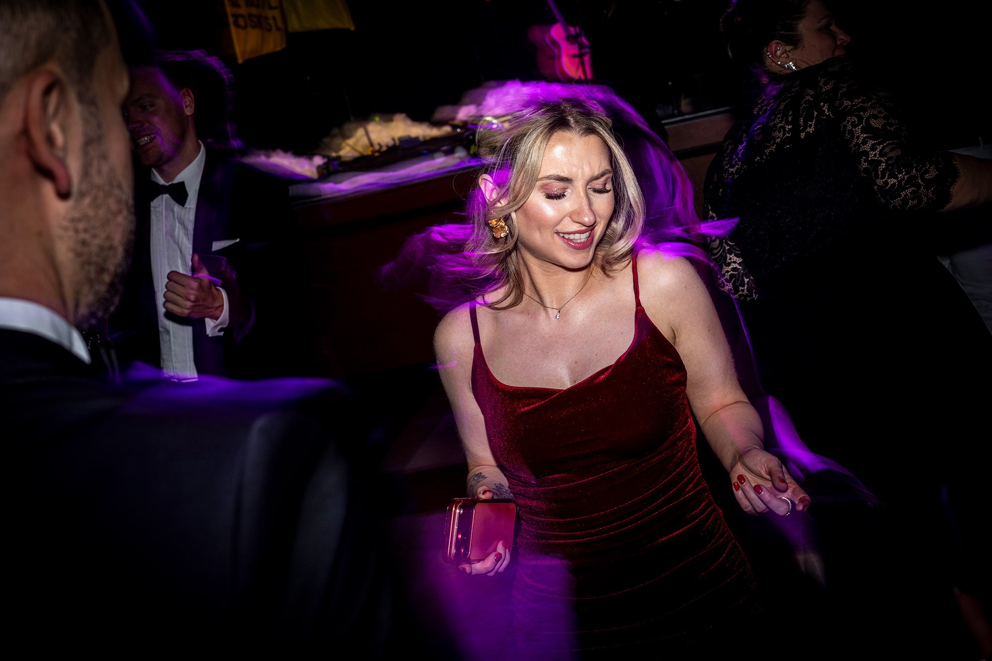 Corporate conference gala afterparty with guests dancing under colorful stage lighting.