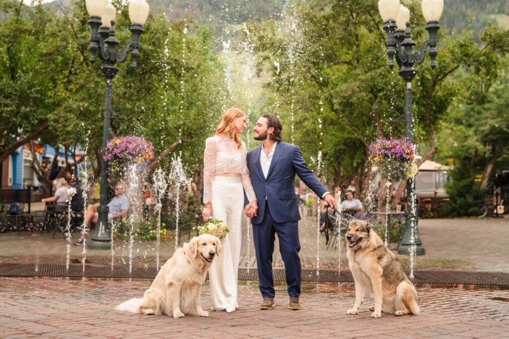Couple with dogs by a fountain at an Aspen family portrait location