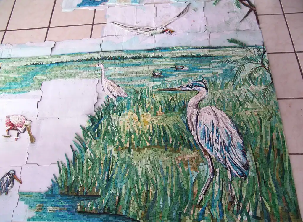 Heron mosaic artwork in a natural wetland setting.