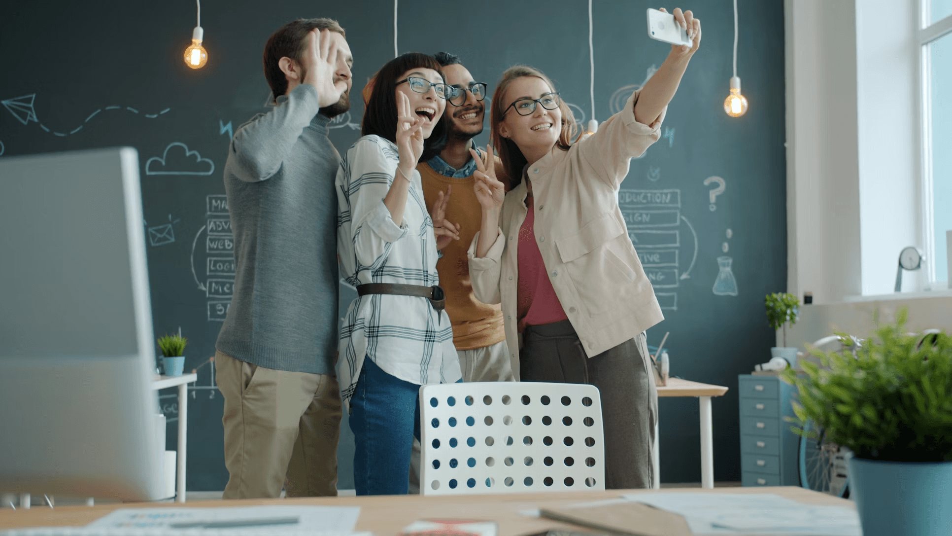 Four smiling people standing in a modern office.