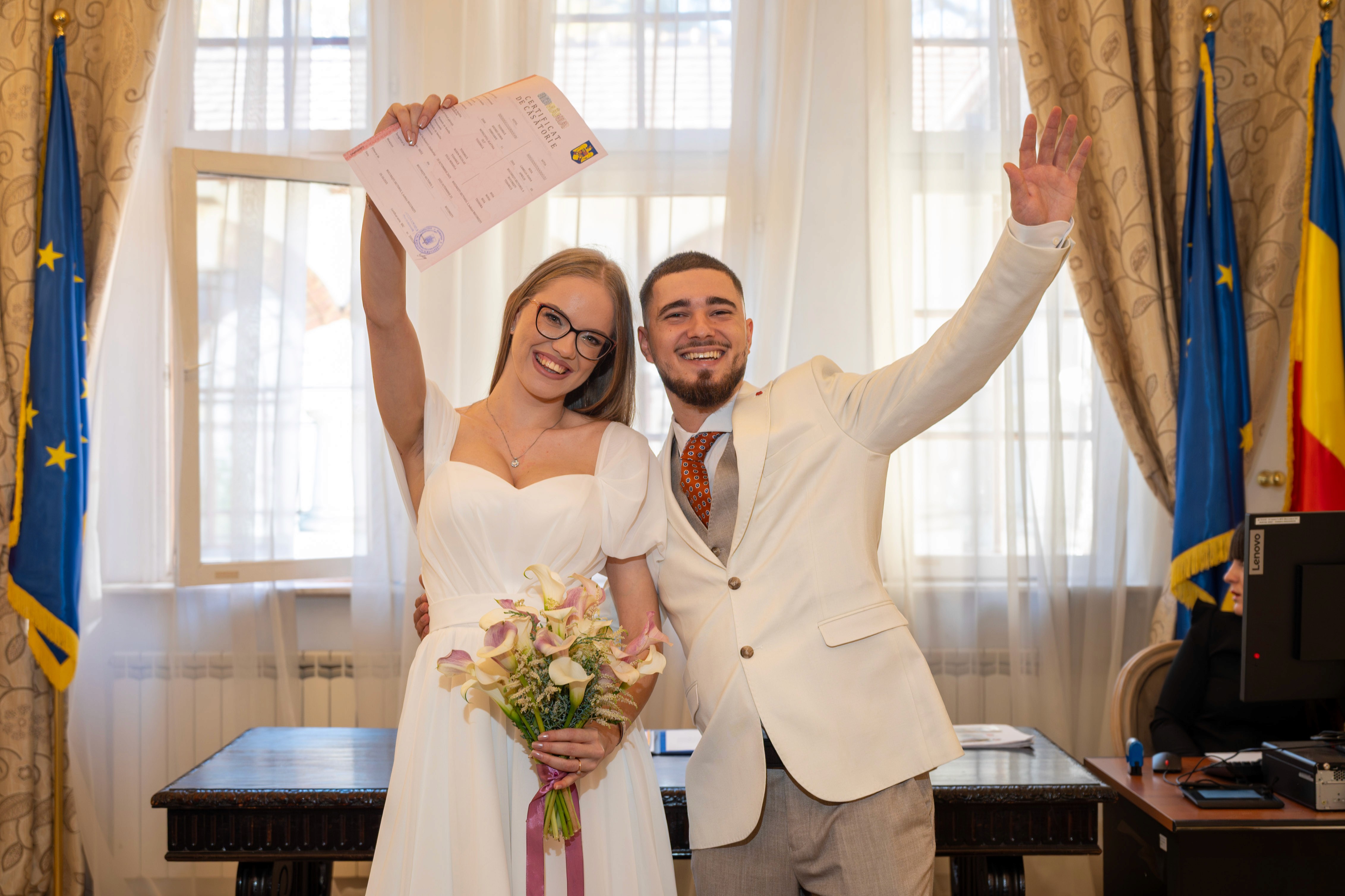Cuplu proaspăt căsătorit ridicând certificatul de căsătorie civilă.