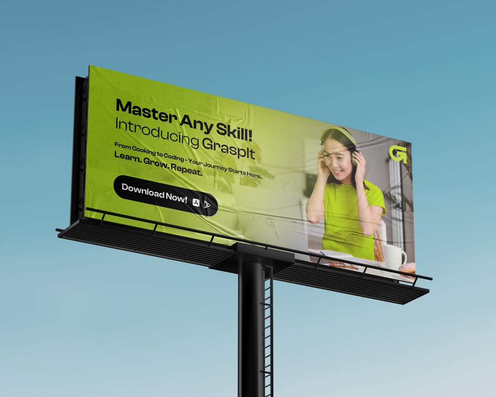 A large billboard against a clear blue sky displays an advertisement with a green and white color scheme, featuring a person wearing headphones and promoting skill mastery with the brand name "GraspIt," including a "Download Now!" call-to-action button.
