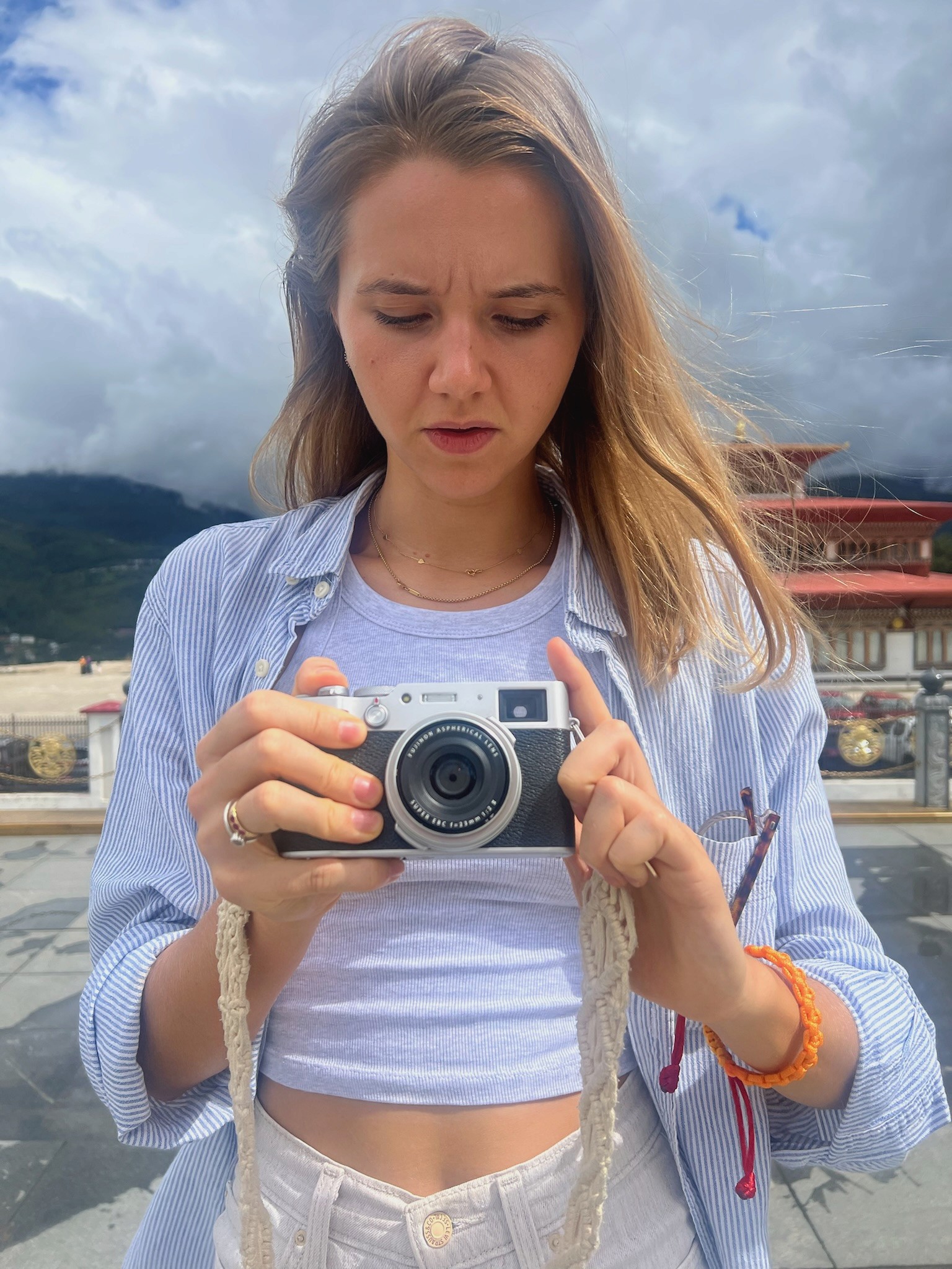I am looking down while holding a camera, with Bhutanese mountains behind her.