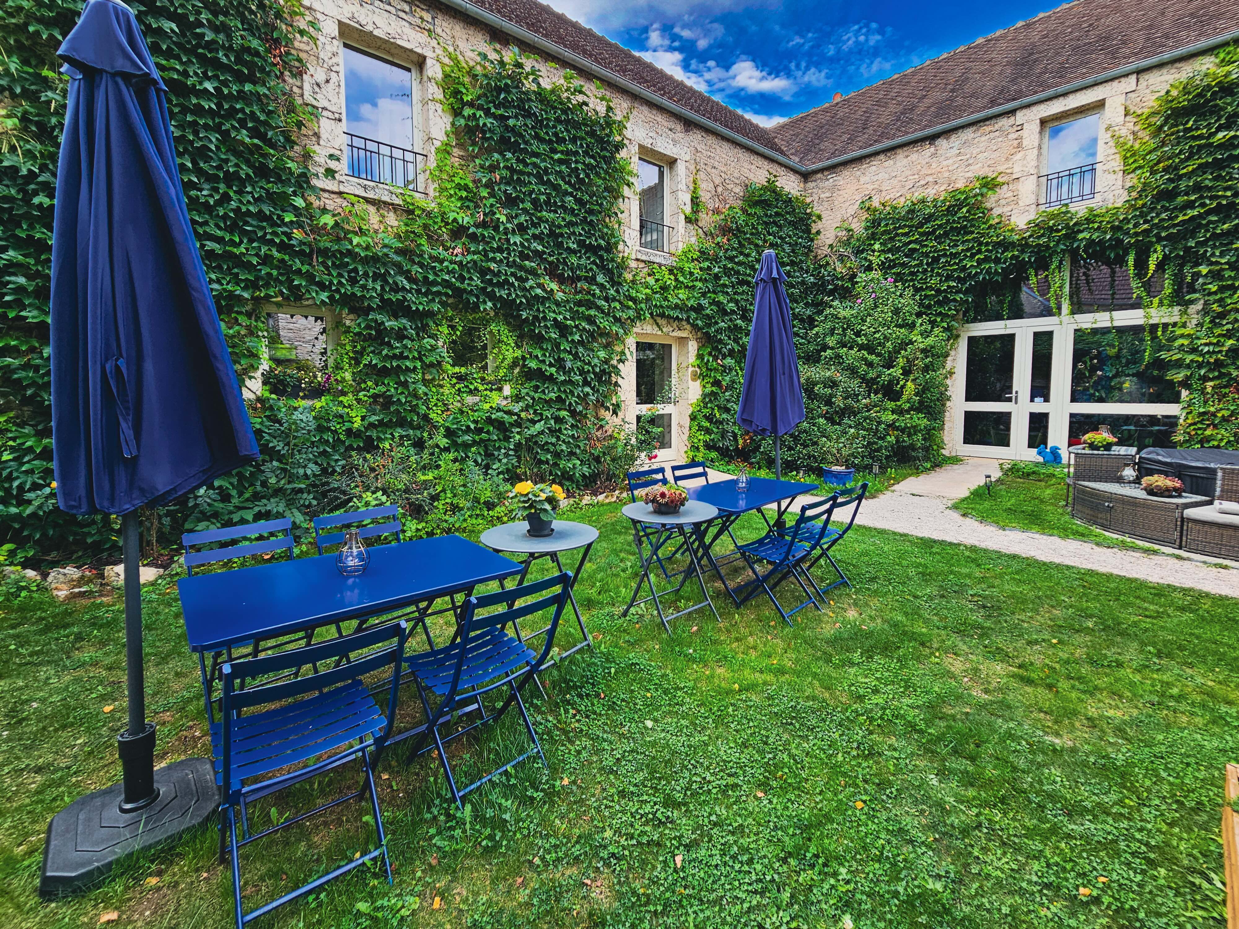 Terrasse avec tables bleues et parasol.