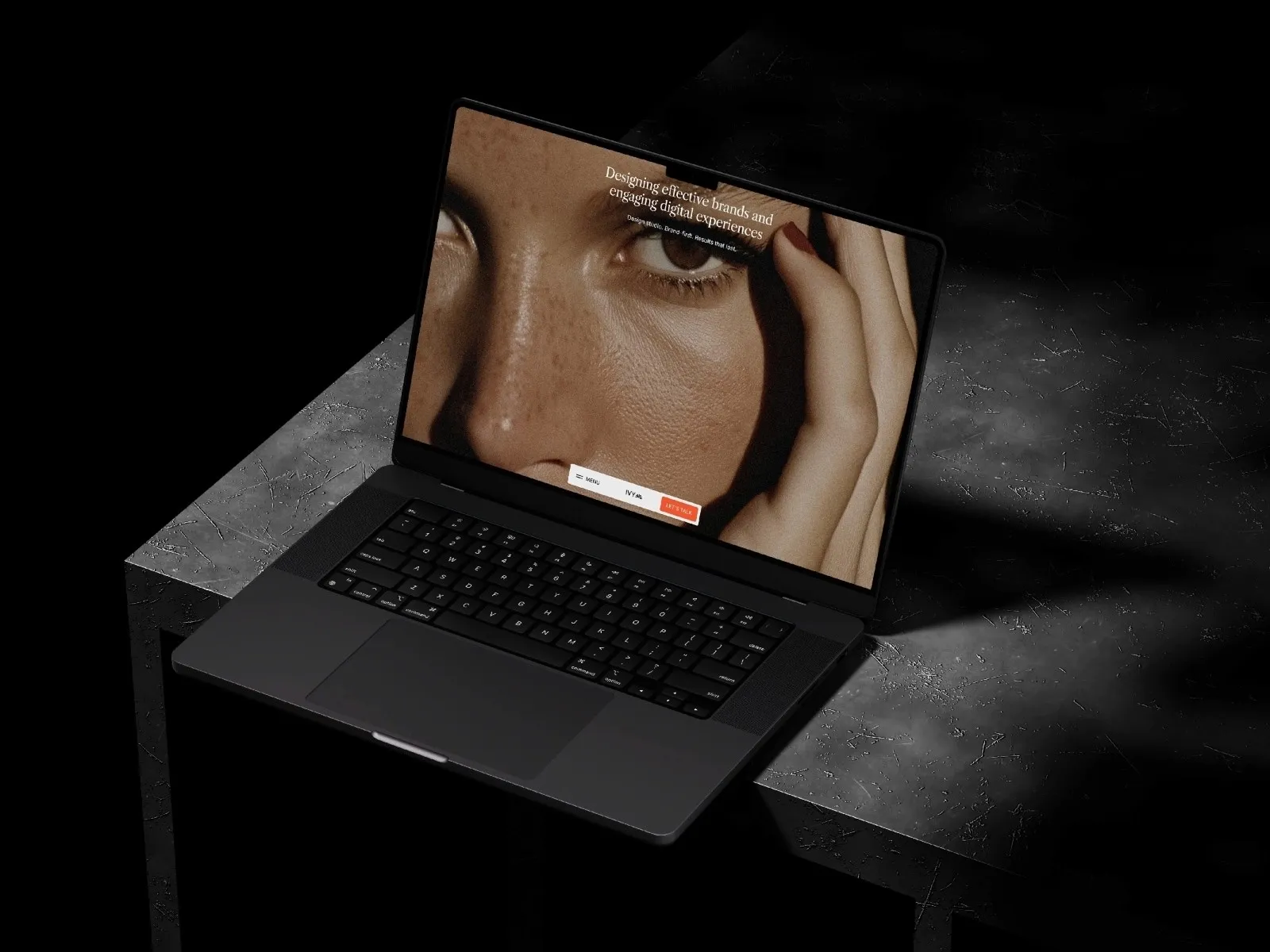 Open laptop on a dark table, displaying a close-up photo of a face.